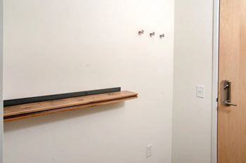 A white wall with a brown shelf and a door.